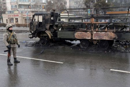 © Reuters. A Kazakh law enforcement officer stands guard near a burnt truck while checking vehicles in a street following mass protests triggered by fuel price increase in Almaty, Kazakhstan January 8, 2022. REUTERS/Pavel Mikheyev