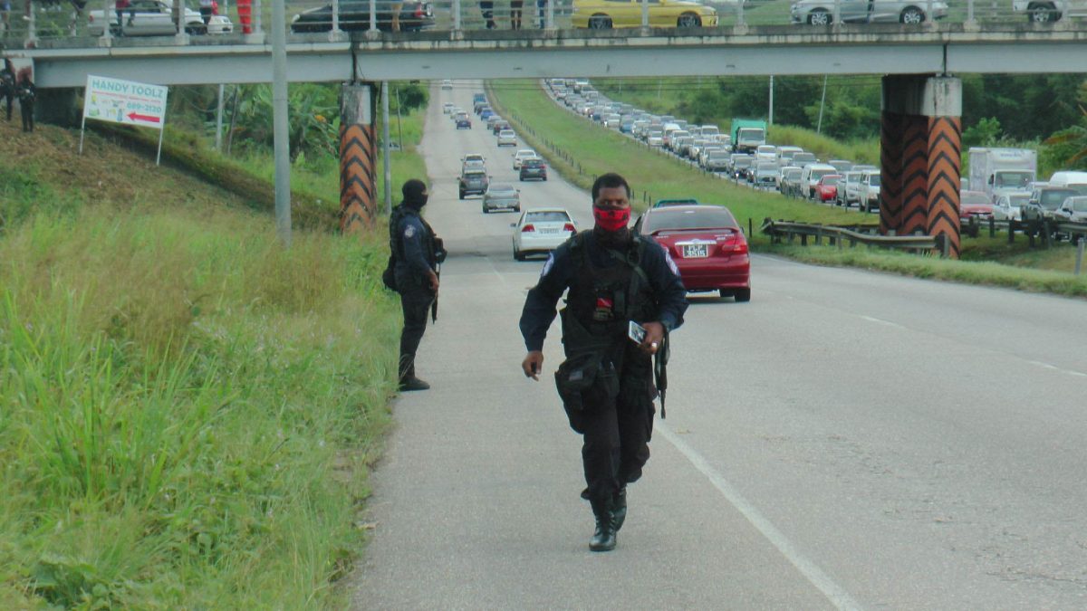 Police officers on the Sir Solomon Hochoy Highway, Couva after the shootout between police and bandits, yesterday.