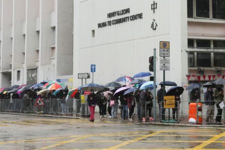 People holding umbrellas and wearing face masks queue outside a COVID-19 community testing centre following the outbreak in Hong Kong, China Feb 19, 2022. (Photo: Reuters/Lam Yik)