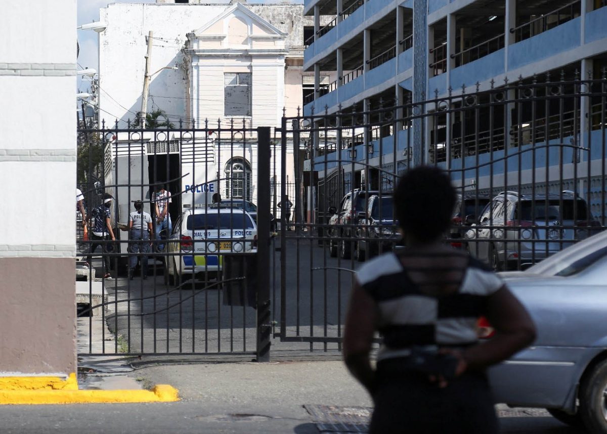 A woman watches as alleged gang members step out of a police truck after arriving at court, in Kingston, Jamaica January 28, 2022. REUTERS/Stringer