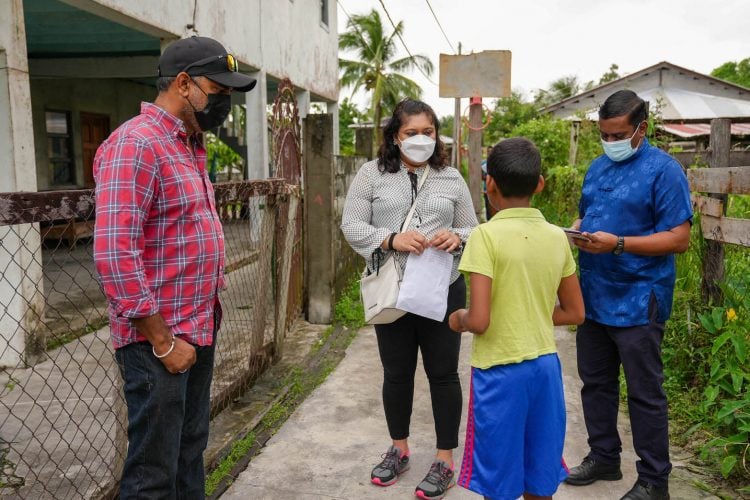 Education Minister Priya Manickchand accompanied by Education Officers speaking with a pupil during an outreach on Friday (Ministry of Education photo)