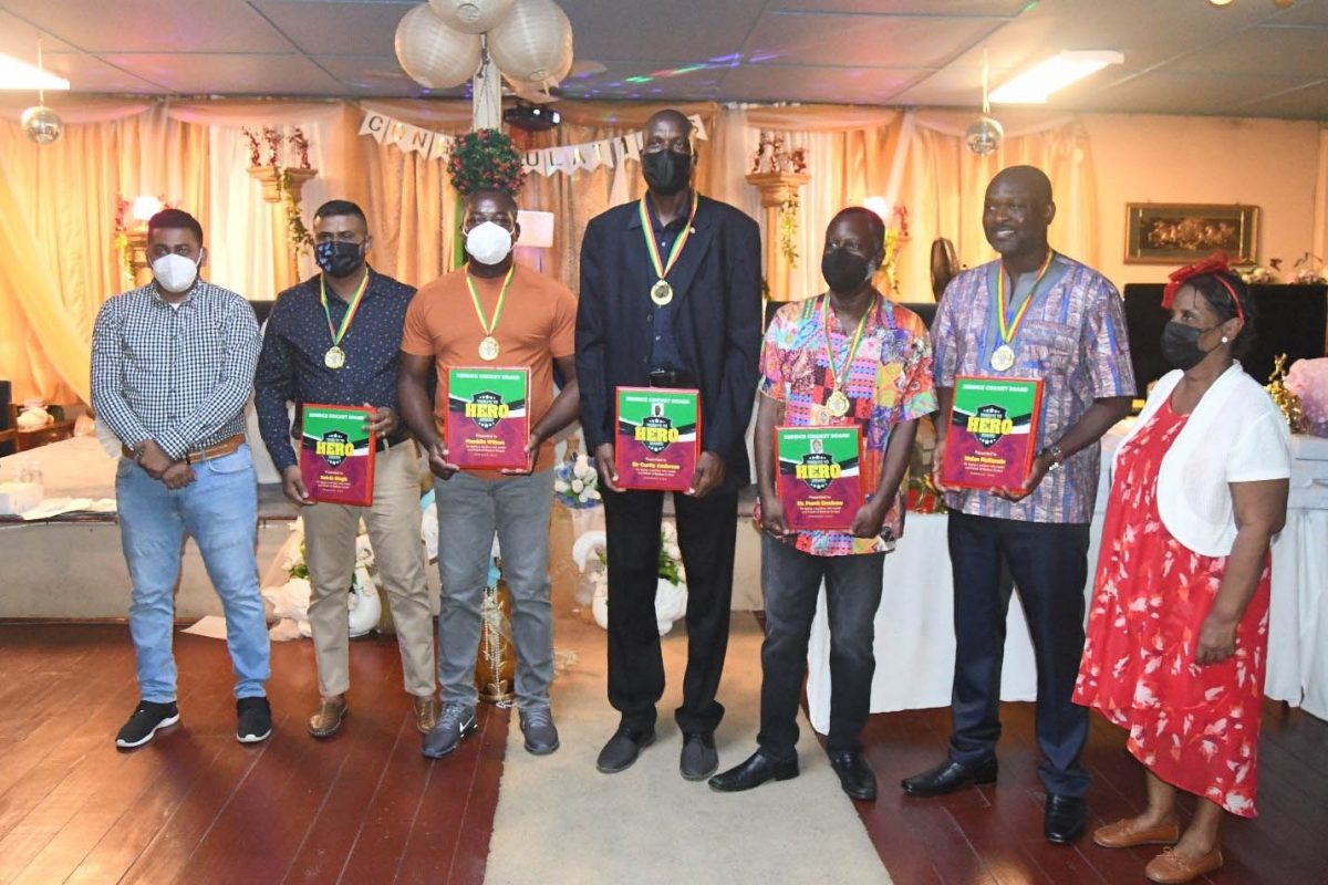 Four of the awardees, Sir Curtly Ambrose (center), Nolan McKenzie (2nd right), Dr. Frank Denbow (3rd right), Franklin Wilson (3rd left) and a representative of Kelvin Singh (2nd left) pose with BCB Secretary Ms. Angela Haniff (right) and BCB Executive, Ameer Rahaman (left).   