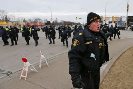A police officer reacts on the road leading to the Ambassador Bridge, which connects Detroit and Windsor, after police cleared demonstrators, during a protest against coronavirus disease (COVID-19) vaccine mandates, in Windsor, Ontario, Canada February 13, 2022. REUTERS/Carlos Osorio
