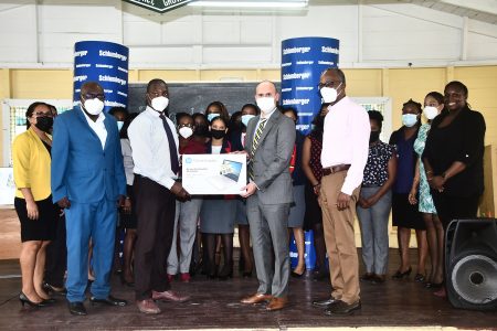 Managing Director of Schlumberger  Ernesto Cuadros (second from right in front row) hands over one of the computers to the Headteacher of the Houston Secondary School,  Kevin Williamson. (Ministry of Education photo)