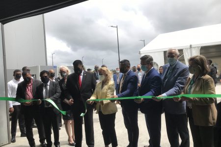 President Irfaan Ali cuts the ribbon for the launch of the Baker Hughes Guyana Supercentre as company executives and special invitees assist
