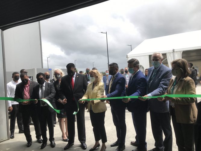 President Irfaan Ali cuts the ribbon for the launch of the Baker Hughes Guyana Supercentre as company executives and special invitees assist
