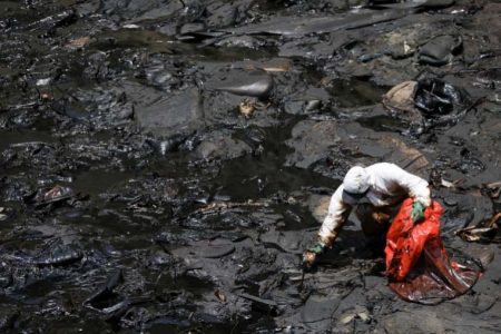 A worker cleans up an oil spill at the Peruvian beach in Ventanilla [Pilar Olivares/Reuters]