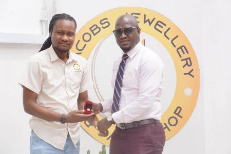 Representative of Jacobs Jewellery Dellon Caesar (left) presenting one of the four championship rings to tournament coordinator Rawle Toney at the company’s Pike Street Kitty location