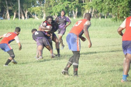 The Guyana Defence Force players attempt to bring down Theo Henry (with ball)