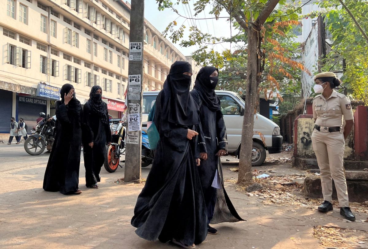 FILE PHOTO: Hijab-wearing students arrive to attend classes as a policewoman stands guard outside a government girls school after the recent hijab ban, in Udupi town in the southern state of Karnataka, India, February 16, 2022. REUTERS/Sunil Kataria