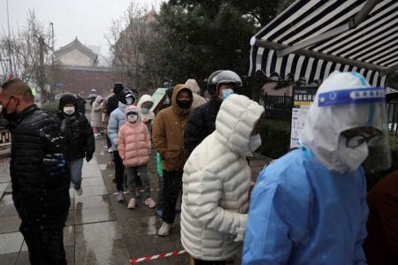 People line up amid snowfall at a mobile nucleic acid testing site, following the coronavirus disease (COVID-19) outbreak, in Beijing, China March 18, 2022. REUTERS/Tingshu Wang