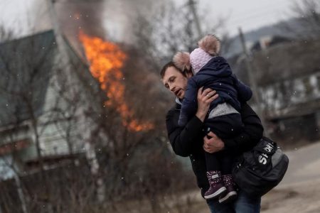 A man and a child escape from the town of Irpin, after heavy shelling on the only escape route used by locals, while Russian troops advance towards the capital, in Irpin, near Kyiv, Ukraine March 6, 2022. REUTERS/Carlos Barria