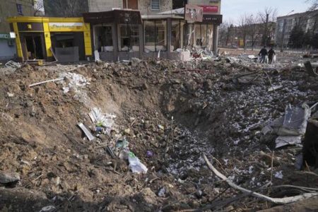 People walk past a crater from the explosion in Mira Avenue (Avenue of Peace) in Mariupol, Ukraine, 13 March, 2022. AP