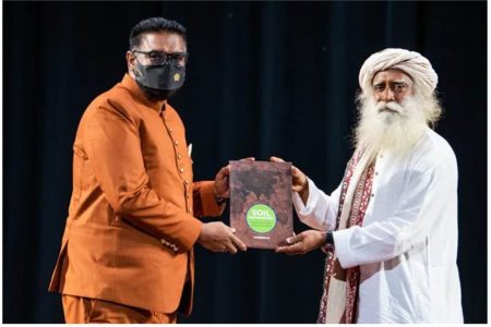 President Irfaan Ali receiving a copy of famous wellness and yoga master Jagadish ‘Sadhguru’ Vasudev’s book at the National Cultural Centre on Saturday. Sadhguru led a delegation, which included Trinidad soca star and yogi Machel Montano, that met with President Ali and his Cabinet yesterday. A Memorandum of Understanding was signed by Minister of Agriculture Zulfikar Mustapha and Sadhguru in support of the latter’s ‘Save Soil’ movement. ‘Save Soil’ is a global movement launched by Sadhguru, to address the soil crisis by bringing together people from around the world to stand up for soil health, and supporting leaders of all nations to institute national policies and actions toward increasing the organic content in cultivable Soil. Supporting partners include the United Nations Convention to Combat Desertification, the UN Environment Programme – Faith for Earth, the World Food Programme, Partnerships For Change, and International Union for Conservation of Nature and Global Citizen Forum. (Department of Public Information photo) 