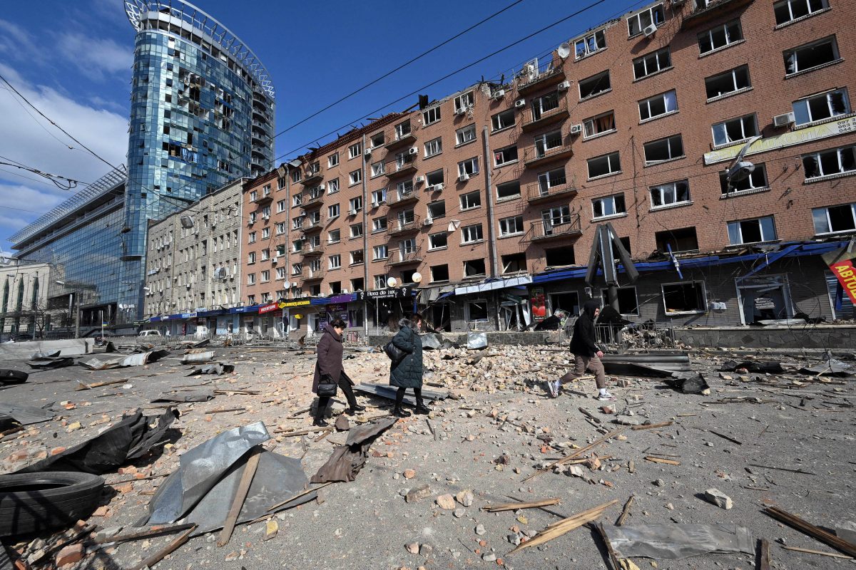 People walk by a building damaged by shelling amid Russian invasion of Ukraine in Kyiv on March 17, 2022, as Russian troops try to encircle the Ukrainian capital as part of their slow-moving offensive (AFP photo)

