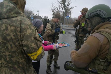 A woman offers sweets to Ukrainian servicemen, in the village of Yasnohorodka in the Kyiv region, Ukraine, March 2. REUTERS/Maksim Levin