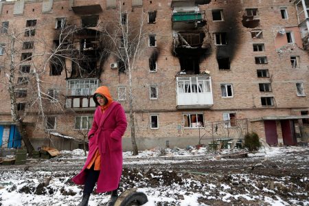 A woman walks in front of a residential building which was damaged during Ukraine-Russia conflict in the separatist-controlled town of Volnovakha in the Donetsk region, Ukraine March 11, 2022. (REUTERS)