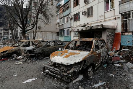 Destroyed cars are seen in front of an apartment building which was damaged during Ukraine-Russia conflict in the besieged southern port city of Mariupol, Ukraine on 27 March, 2022 (Reuters)
