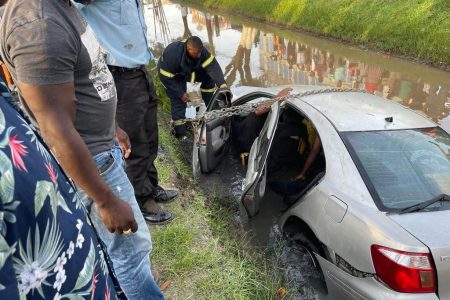 Firefighters rescuing the victims who were trapped in the car. (Guyana Fire Service photo)