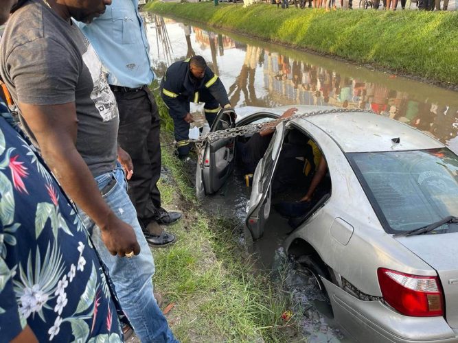 Firefighters rescuing the victims who were trapped in the car. (Guyana Fire Service photo)