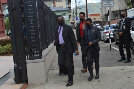 Minister of National Security Fitzgerald Hinds (left) is escorted by his security to the Red House for yesterday’s sitting of the House of Representatives.