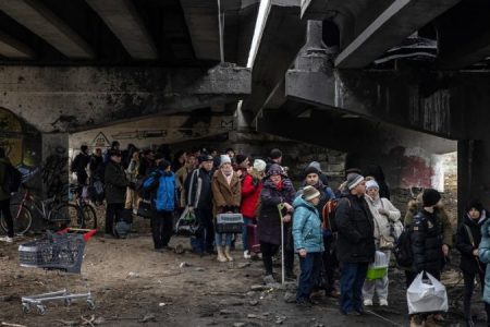 People with their luggage wait under a destroyed bridge as they flee from the frontline town of Irpin, Kyiv region, Ukraine, 7 March 2022. Irpin, the town which is located near Kyiv city had heavy fighting for almost a week between Ukrainian and Russian militaries forcing thousands of people to escape from the town. [EPA-EFE/ROMAN PILIPEY]