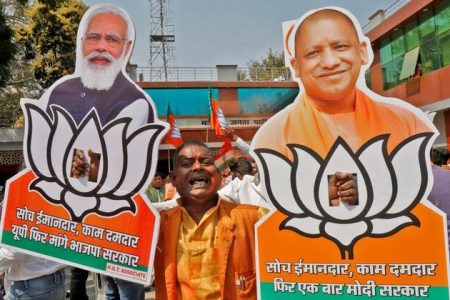 A supporter of India's ruling party Bharatiya Janata Party (BJP) displays cut-outs of Prime Minister Narendra Modi and Chief Minister of Uttar Pradesh Yogi Adityanath as he celebrates after learning the initial poll results outside its party office in Lucknow, India, March 10, 2022. REUTERS/Pawan Kumar