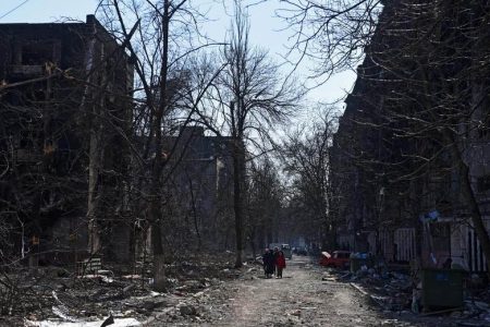 Local residents walk near residential buildings which were damaged in the besieged southern port city of Mariupol, Ukraine, March 18. REUTERS/Stringer