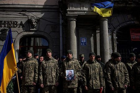 Soldiers, one of them holding a photo of sergeant Kostiantyn Deriuhin, 44, who was killed in battle during Russia's attack on Ukraine, stand guard before a funeral ceremony at Saints Peter and Paul Garrison Church in Lviv, Ukraine, March 27, 2022. REUTERS/Alkis Konstantinidis