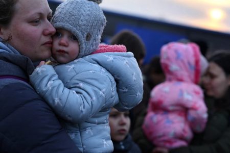 Ukrainian women who were fleeing the Russian invasion of Ukraine hold their children as they arrive at a temporary camp in Przemysl, Poland on March 1, 2022 [Kai Pfaffenbach/ Reuters]