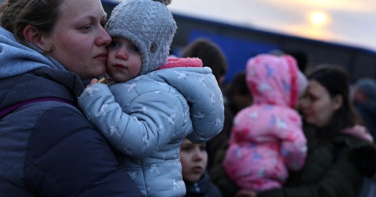 Ukrainian women who were fleeing the Russian invasion of Ukraine hold their children as they arrive at a temporary camp in Przemysl, Poland on March 1, 2022 [Kai Pfaffenbach/ Reuters]