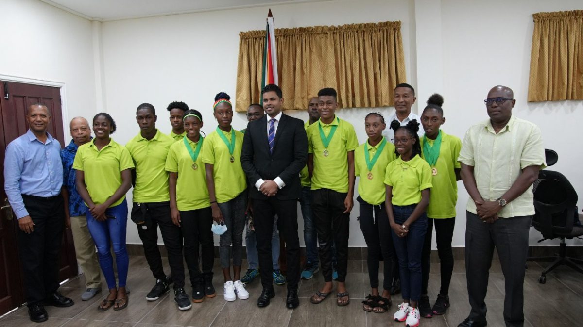 The returning CARIFTA Games athletes pose with Minister of Sport, Charles Ramson Jr, members of the National Sports Commission, and members of the AAG, following a meeting yesterday where the contingent was assured of individual rewards.
