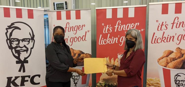 Marketing Officer of KFC Guyana Ltd Pamela Manasseh (left ) delivers a cheque for $250,000 to Guyana Chess Federation Company Secretary Marcia Lee 