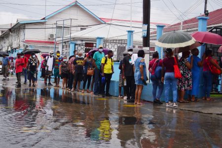 Persons standing outside the flooded New Market Street entrance of the Georgetown Public Hospital Corporation waiting to be let in yesterday. (Orlando Charles photo)