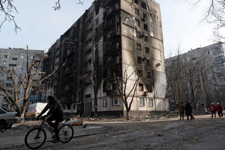 A local resident rides a bicycle past an apartment building damaged during Ukraine-Russia conflict in the besieged southern port city of Mariupol, Ukraine March 31, 2022. REUTERS/ Alexander Ermochenko