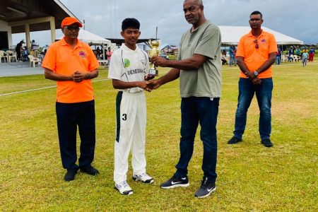 Man of the Match, Darwin LaRose of Demerara Under-15 receives his award from former Test bowler, Clyde Butts
