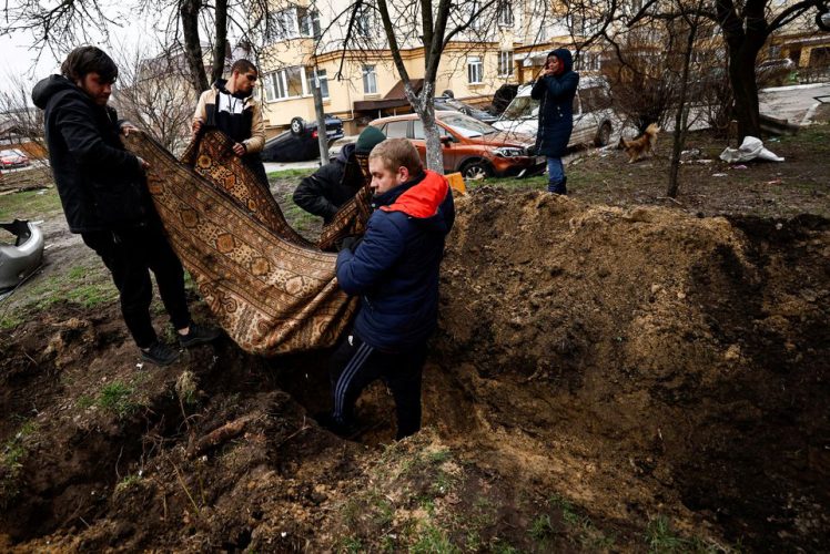 Serhii Lahovskyi, 26, and other residents carry the body of Ihor Lytvynenko, who according to residents was killed by Russian Soldiers, after they found him beside a building’s basement, to bury him at the garden of residential building, amid Russia’s invasion of Ukraine, in Bucha, Ukraine April 5, 2022. REUTERS/Zohra Bensemra