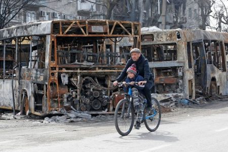 A man and a child ride a bicycle past burnt out buses during Ukraine-Russia conflict in the southern port city of Mariupol, Ukraine April 19, 2022
Image: REUTERS