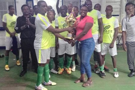 Captain of the Guyana Masters Team Christopher Barnwell receives the trophy in the presence of teammates after defeating SV Ratio FC of Suriname 3-1 to clinch the three match series 2-1
