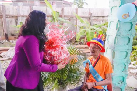 Minister of Human Services and Social Security,  Dr. Vindhya Persaud presenting a hamper to  Hilton ‘Champ’ Lewis (Ministry of Human Services and Social Security photo)