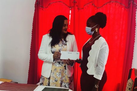 Minister Vindhya Persaud handing over one of the grant to a recipient. 