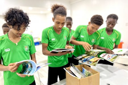 Some members of the Guyana Junior Jaguars football team examining the brochures.