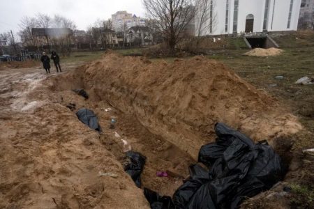Neighbours gather next to a mass grave in Bucha, in the outskirts of Kyiv, Ukraine, Sunday, April 3, 2022. (AP Photo/Rodrigo Abd)