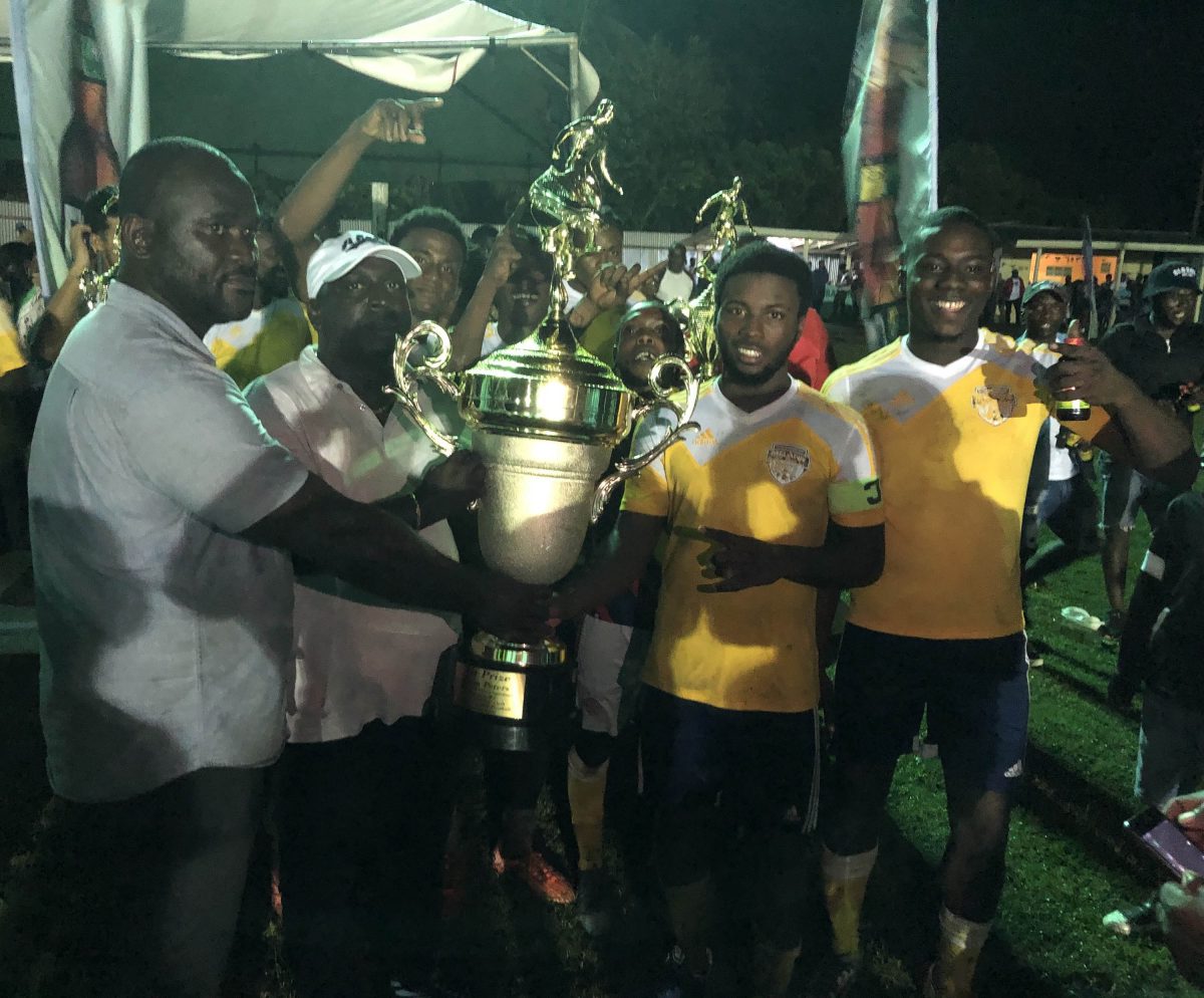 Marlon Forrester (second from right), captain of Melanie receives, the championship trophy in the presence of teammates and officials of the event 