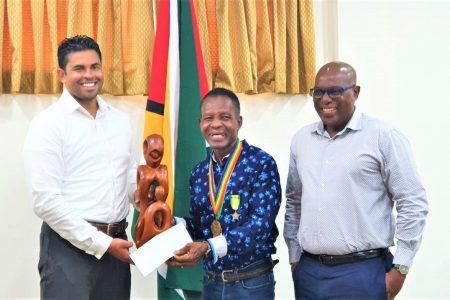 Minister of Sport, Charles Ramson Jr. (left) made the presentation to Olympic medallist Michael Parris in the presence of Director of Sport, Steve Ninvalle.
