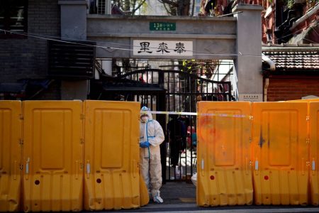A worker in a protective suit stands behind barriers sealing off a residential area under lockdown, following the coronavirus disease (COVID-19) outbreak in Shanghai, China March 29, 2022. REUTERS/Aly Song/File Photo