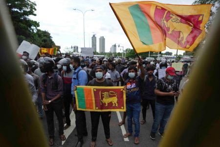 Sri Lankans protest demanding president Gotabaya Rajapaksa resign, behind a police barricade on a street leading to the parliament in Colombo, Sri Lanka, Tuesday, April 5, 2022. (AP Photo/Eranga Jayawardena)
