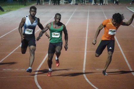 Akeem Stewart (centre) powered across the line ahead of to win the marquee 100m men’s event in 10.40 last evening at the National Track and Field Centre.   (Emmerson Campbell photo)