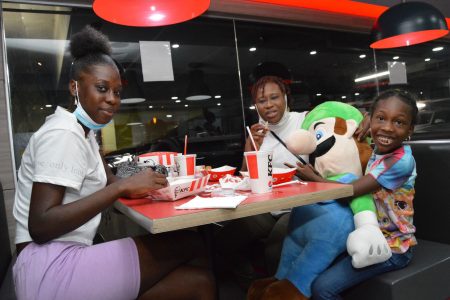 Yvette Sandy, center, with her daughters Makasha Carty, left, and Shawna Sandy enjoy their KFC at MovieTowne, Port-of-Spain, yesterday.