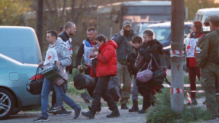 Civilians evacuated from the Azovstal steel plant in Mariupol, accompanied by members of the International Committee of the Red Cross, arrive at a temporary accommodation center in the village of Bezimenne, Ukraine, on May 6.   © Reuters 